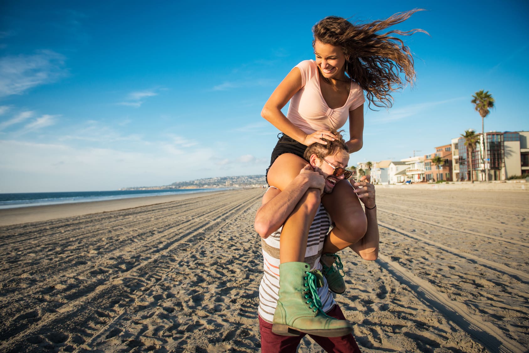 Young man carrying girlfriend on shoulders on San Diego beach