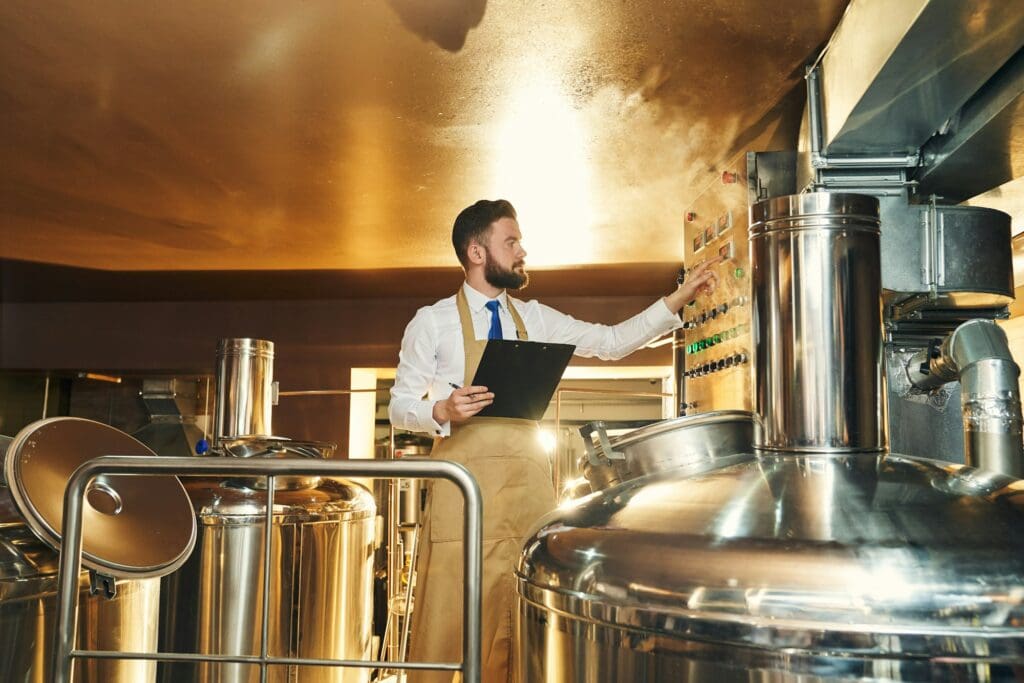 Handsome engineer of brewery inspecting process of brewing